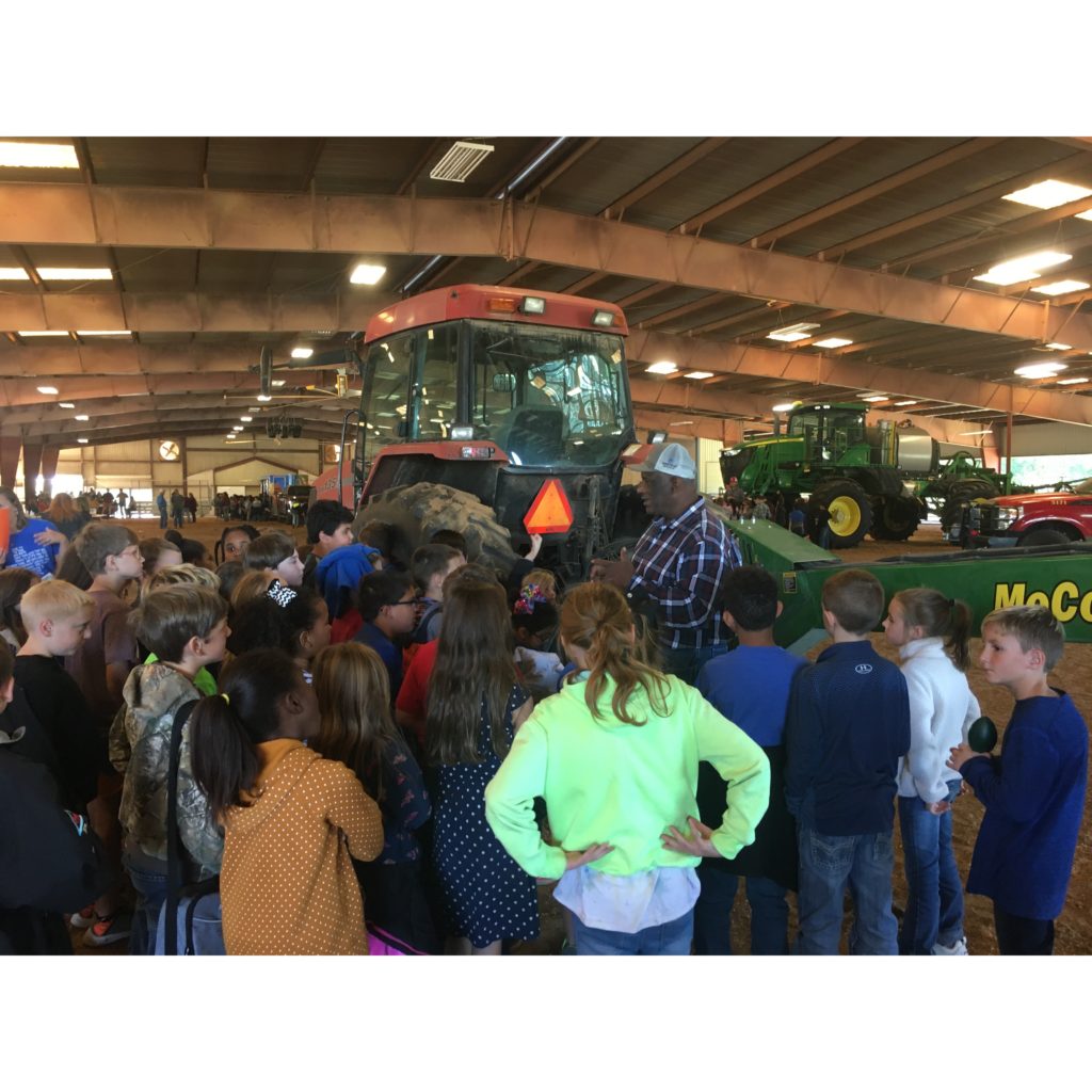 Ag/NR Agent Truman Lamb stands infront of Hay cutter equiptment and a group of 20 third graders.
