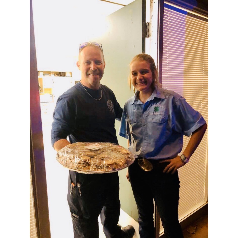 4-H member giving a plate of cookies to a Firefighter.